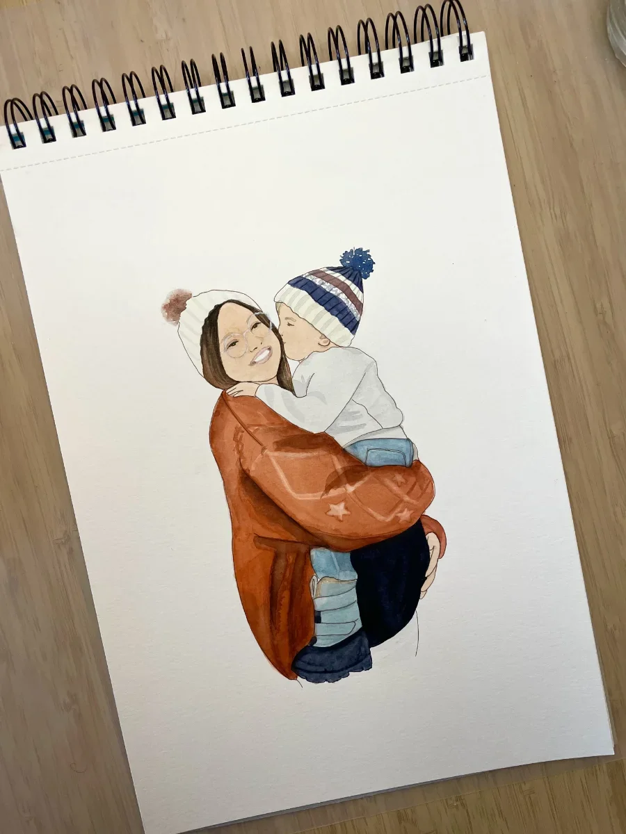 Une illustration d'une femme souriante portant un manteau orange et un bonnet blanc avec une pompon rouge, qui tient un enfant portant un bonnet à rayures bleues, blanches, rouges et une étoile en forme de pompon. L'enfant lui fait un bisou.