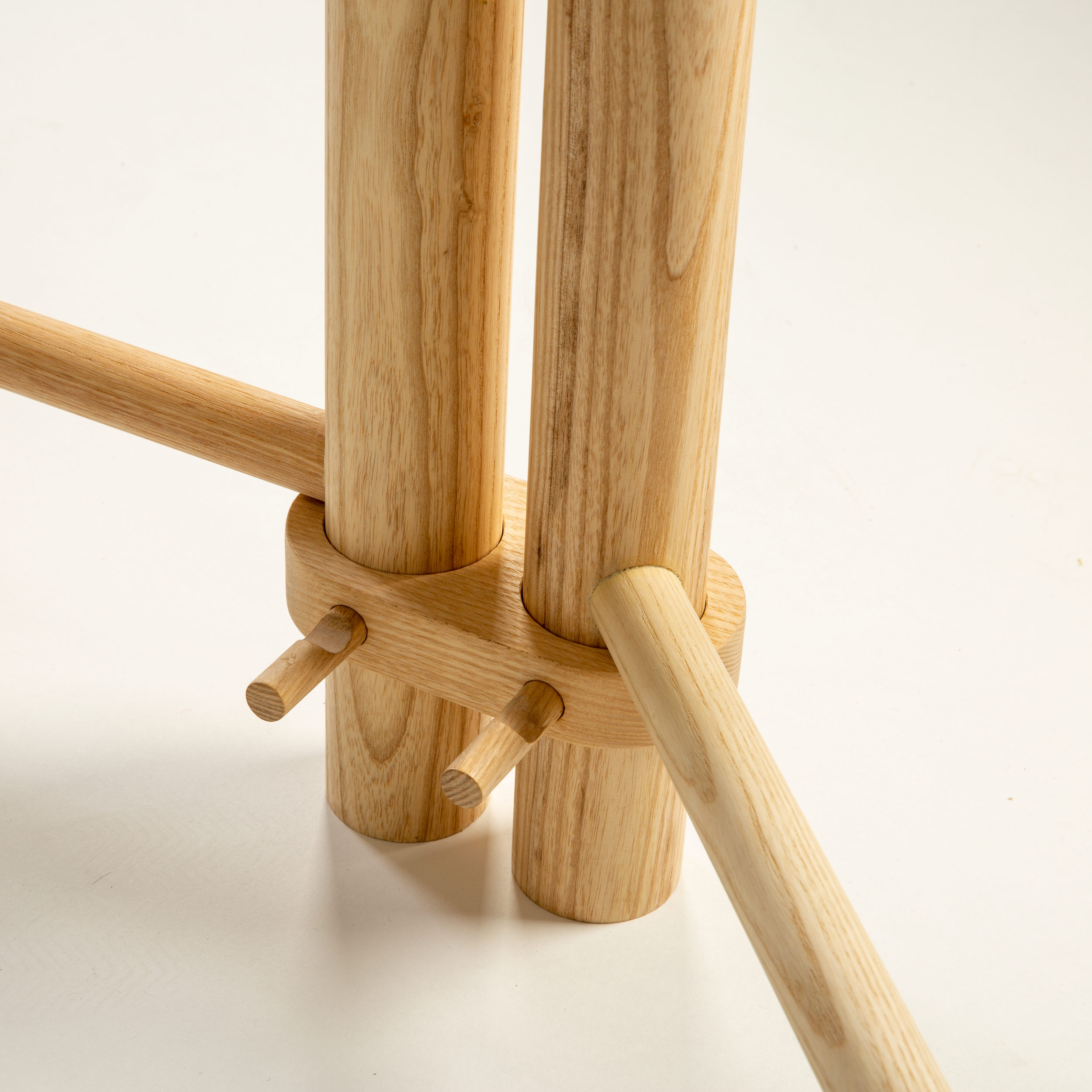 Bespoke retail display design and manufacture for MOO, creating premium merchandising installations that elevate product presentation. Close-up of wooden furniture, showcasing smooth, cylindrical wooden rods and a circular base.