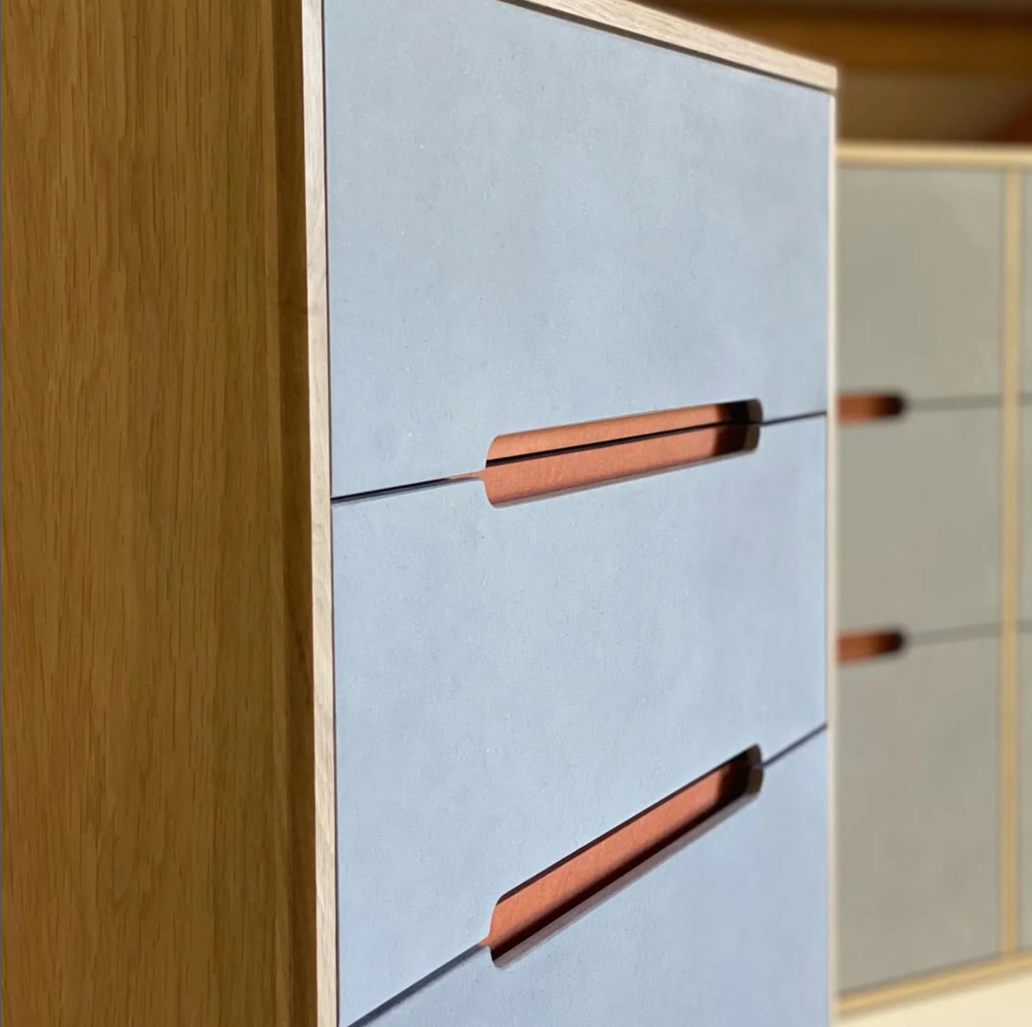 Close-up view of a modern wooden and pastel-colored furniture piece, possibly a desk or cabinet, with a sleek design and smooth surfaces.