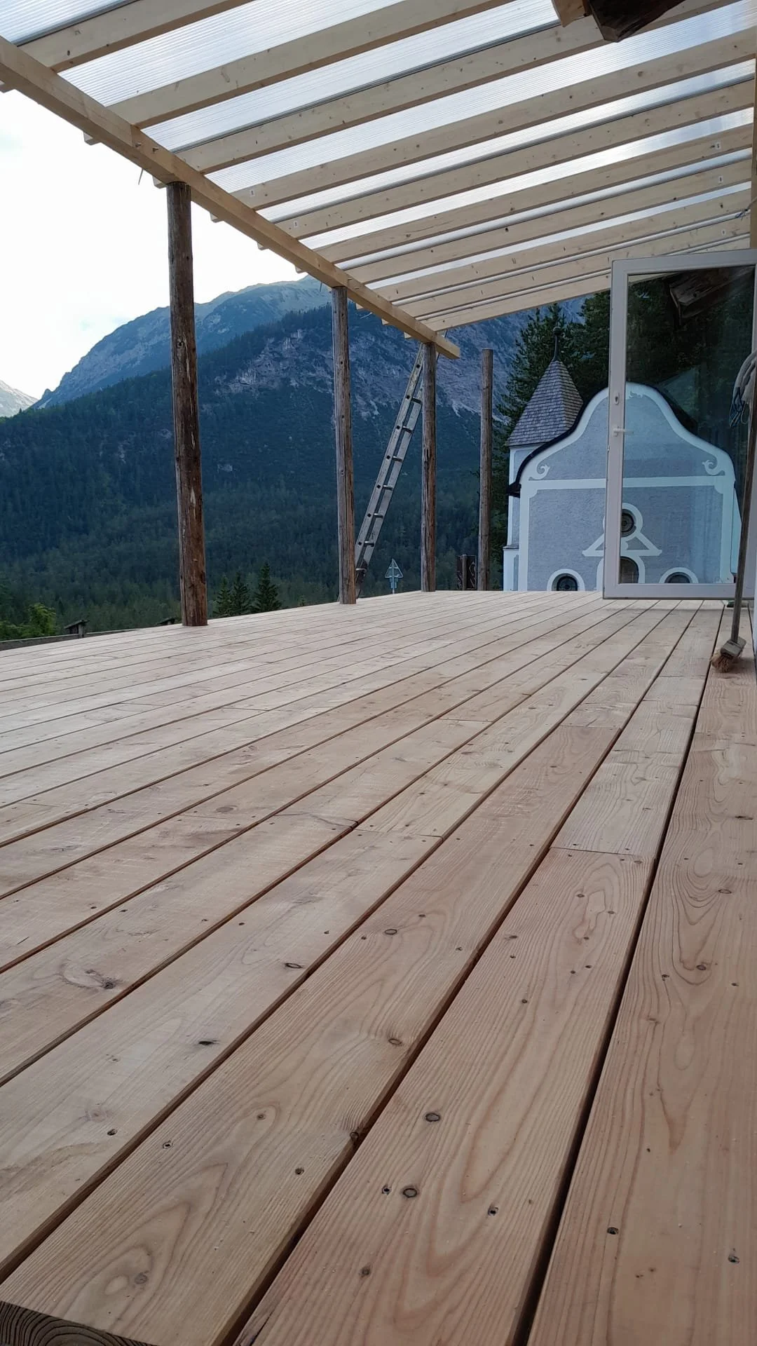 A wooden deck under construction with a mountain view in the background. Austrian challet patio