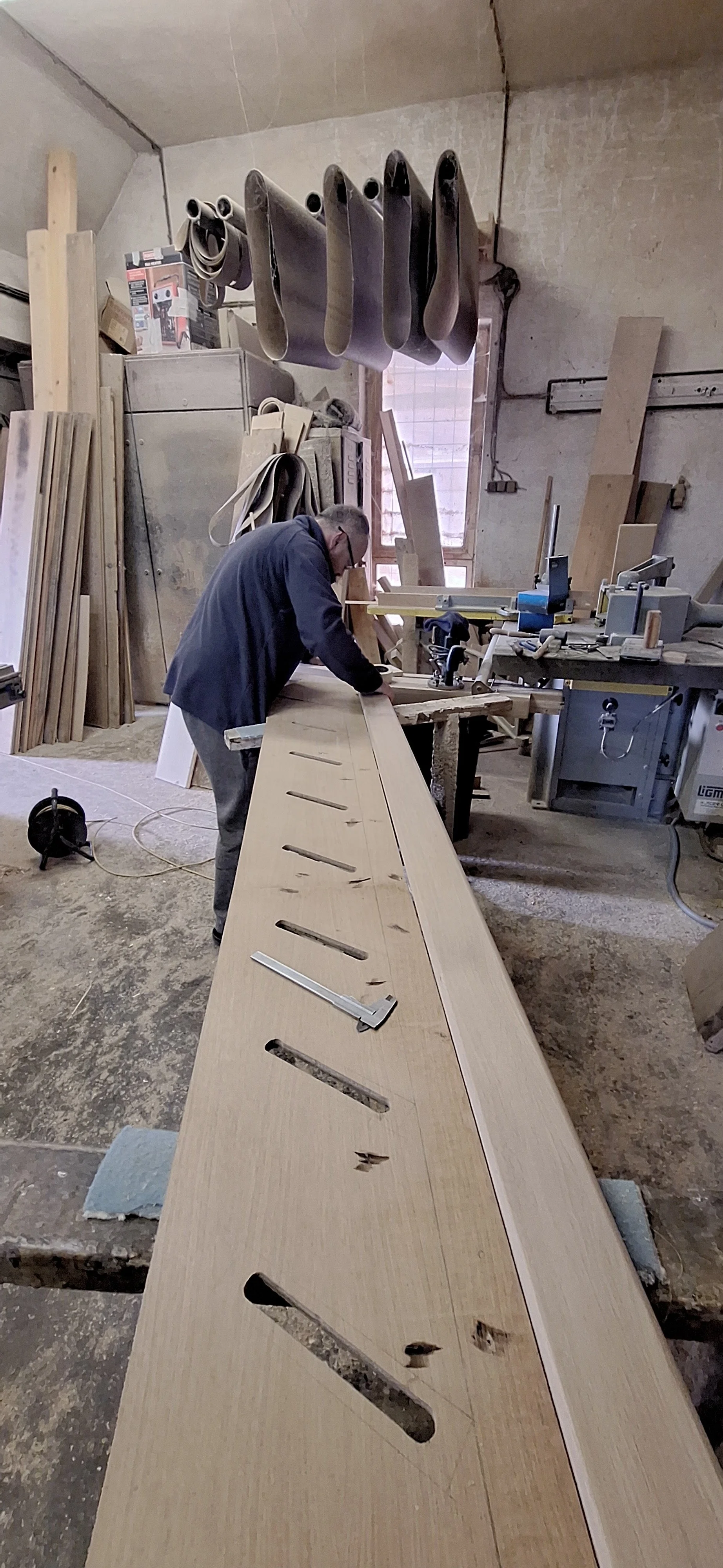 Truhlář v dílně při výrobě dubových schodů. Carpenter in the workshop crafting custom oak stairs.
