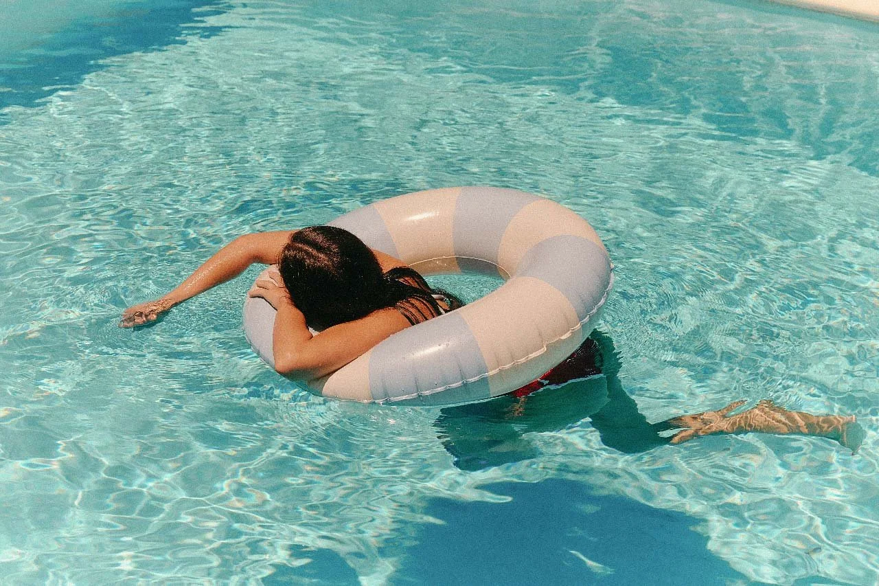 Woman with dark hair resting on a pool float in a swimming pool