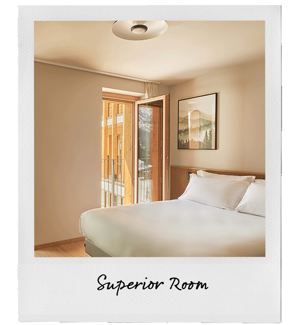 A hotel room with a bed, open balcony door, and mountain landscape picture on the wall.