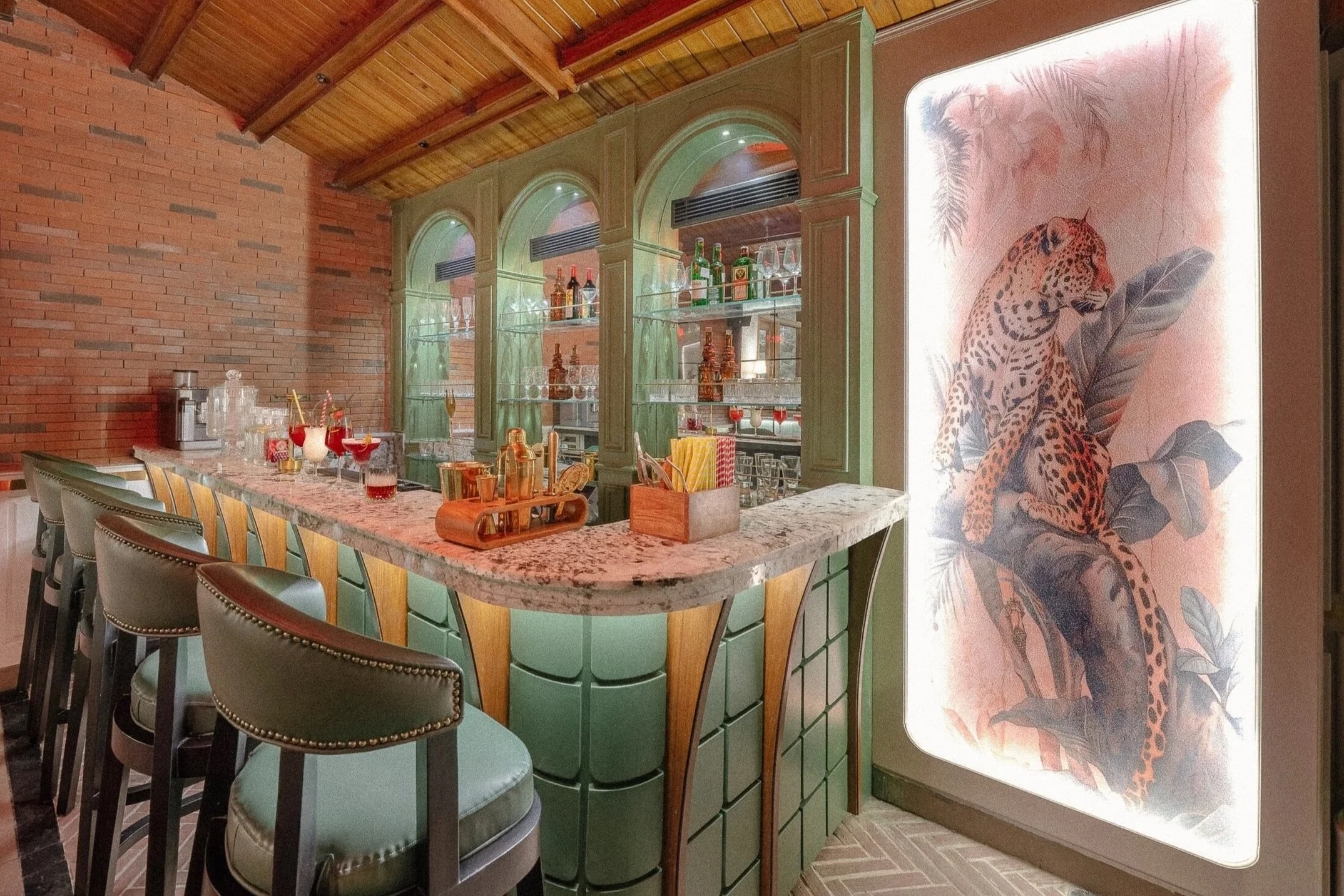 Indoor bar area with a granite counter, green cabinetry, and a mural of a jaguar on the wall.