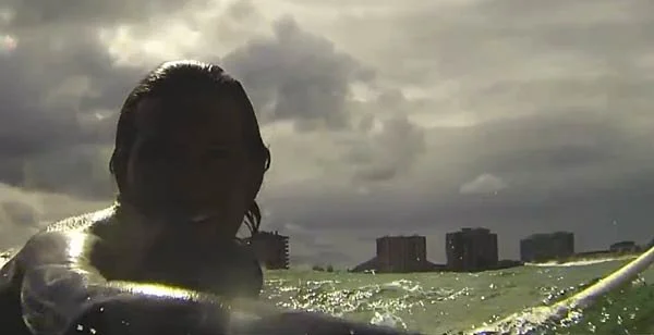 Persona che fa surf in mare con il cielo nuvoloso sullo sfondo.