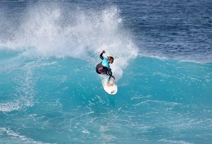 Una surfista che cavalca un'onda nel mare.