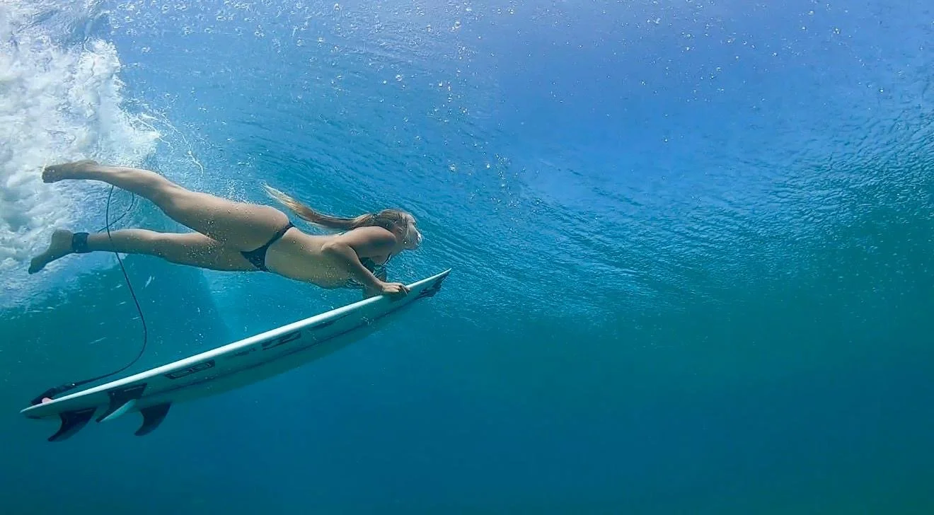 Una donna che nuota sott'acqua mentre utilizza una tavola da surf.
