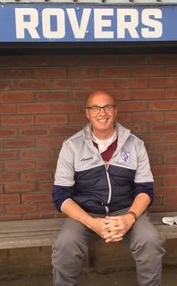 Man sitting on a bench in front of a brick wall with a