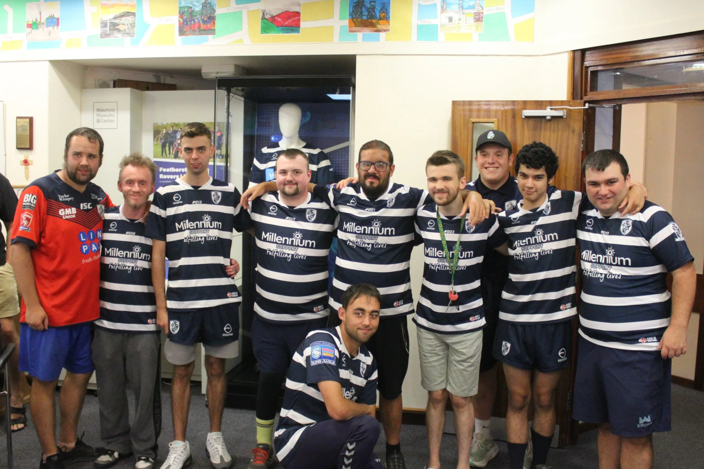 A group of young men stood in a row wearing rugby kits and sportswear