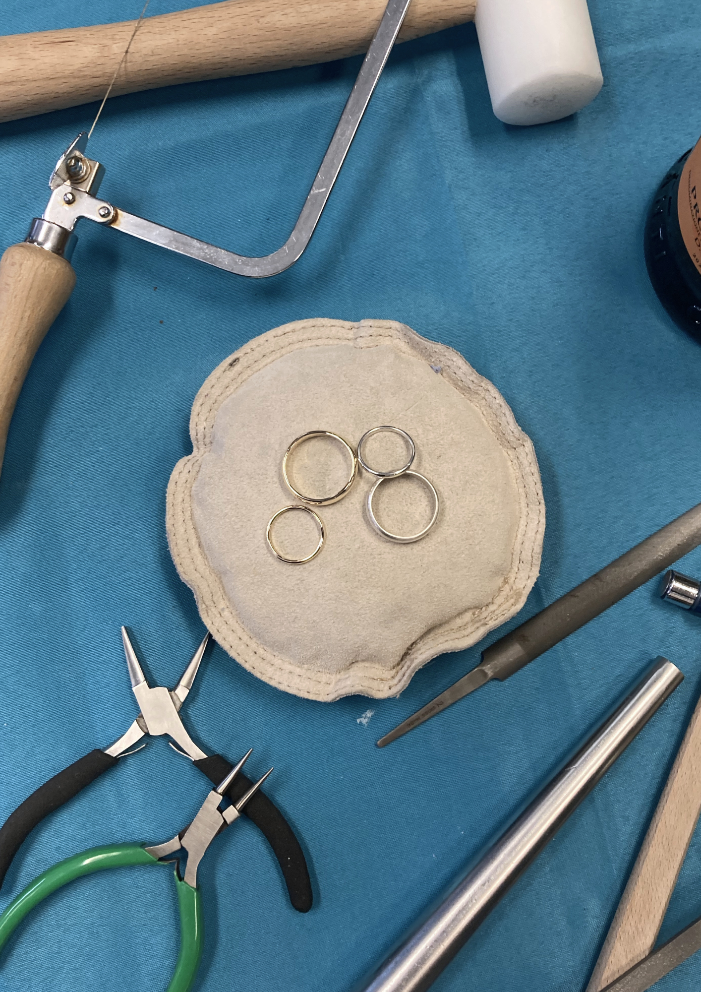 Medical instruments including scissors, forceps, and rings on a blue cloth, with a small padded tray and other tools visible.
