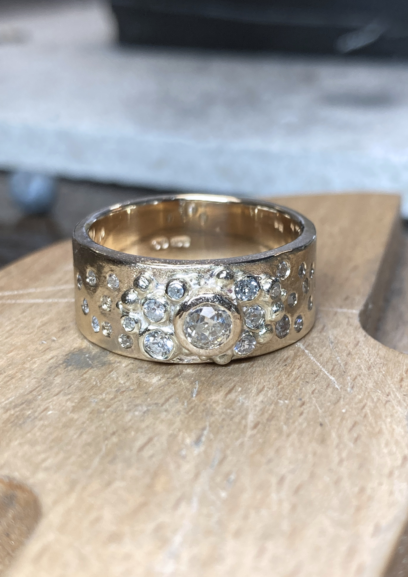 A gold ring encrusted with multiple small diamonds resting on a wooden surface.