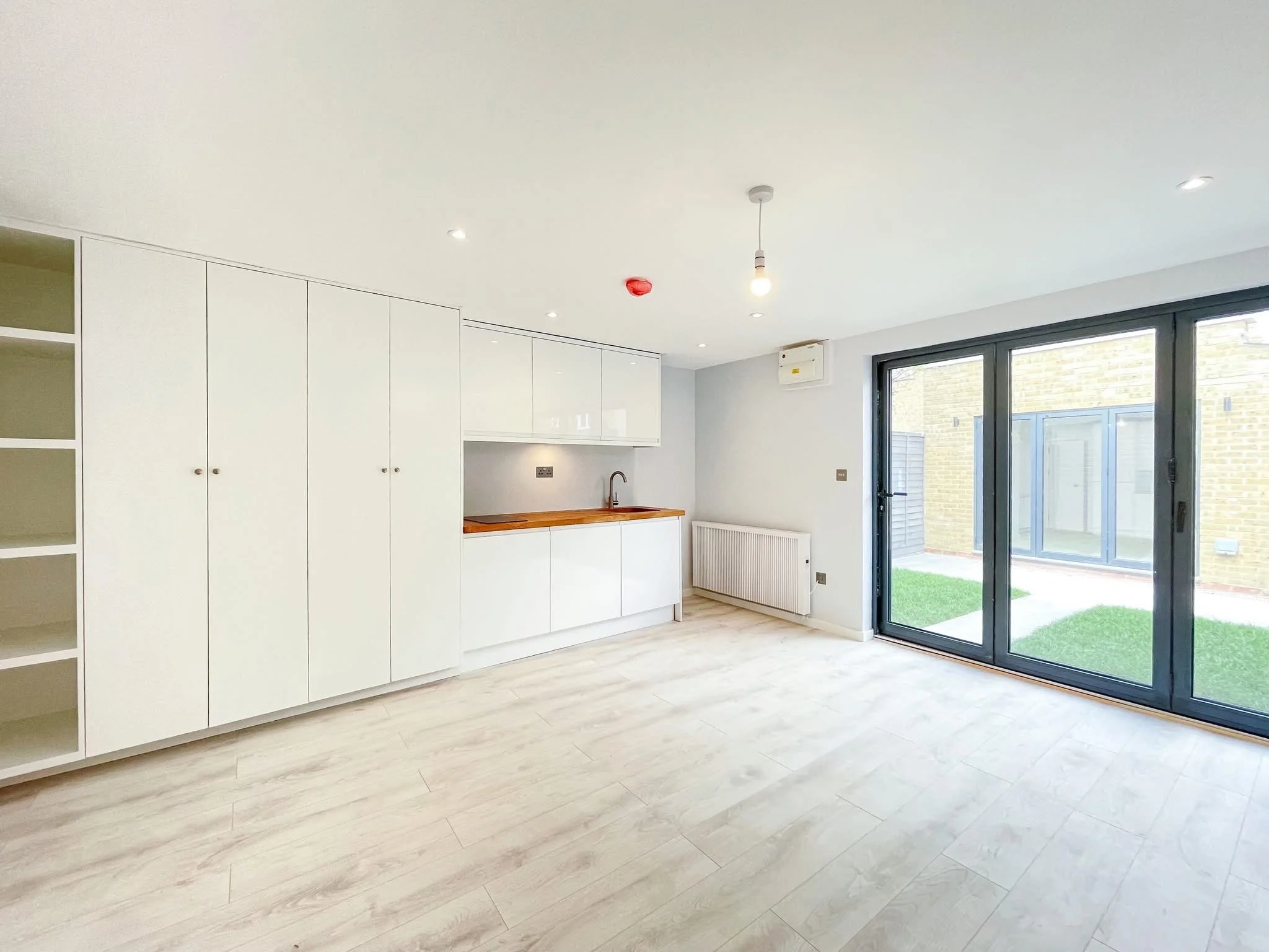 Refurbished rental-ready living space with fitted kitchen and garden doors.