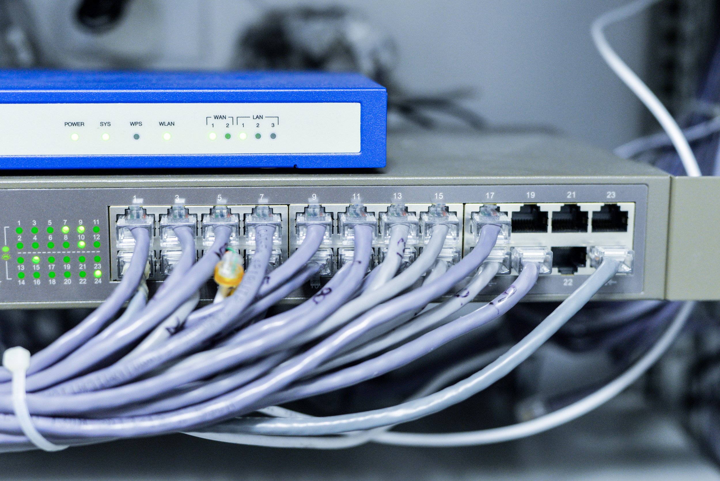 Een netwerk switch met meerdere netwerkabels en verbonden kabels, en een router met indicatielampjes.