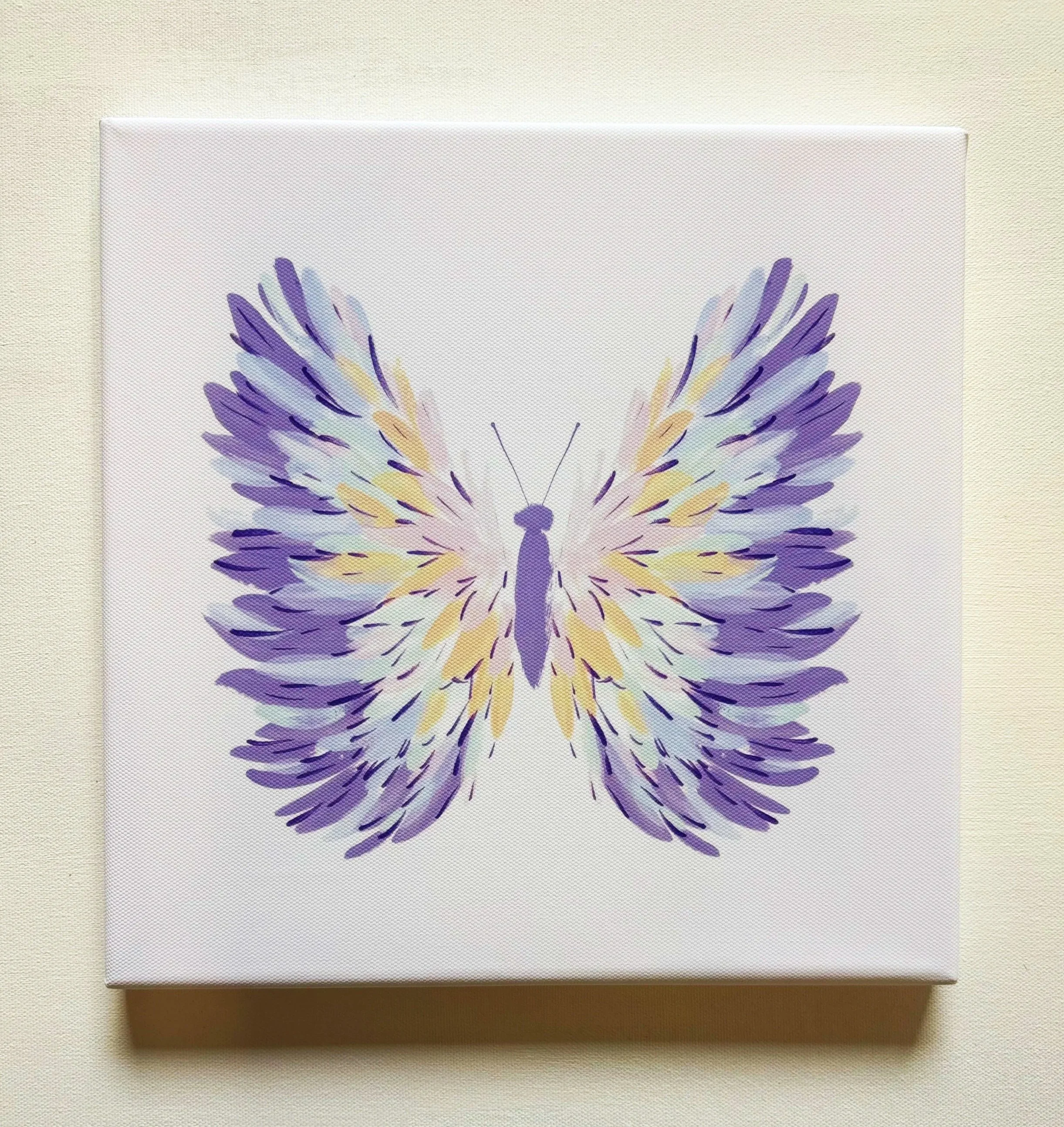 Canvas art featuring a symmetrical, abstract butterfly pattern in purple, yellow, and blue tones, placed on a light, textured background.