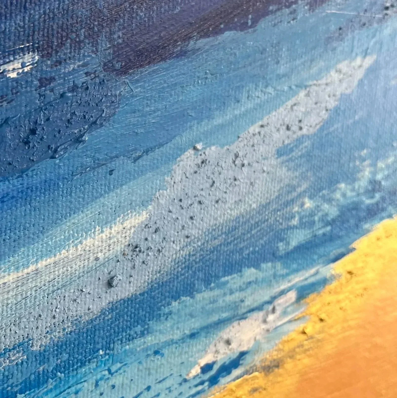 Close-up of an abstract textured surface with shades of blue, black, and yellow paint.