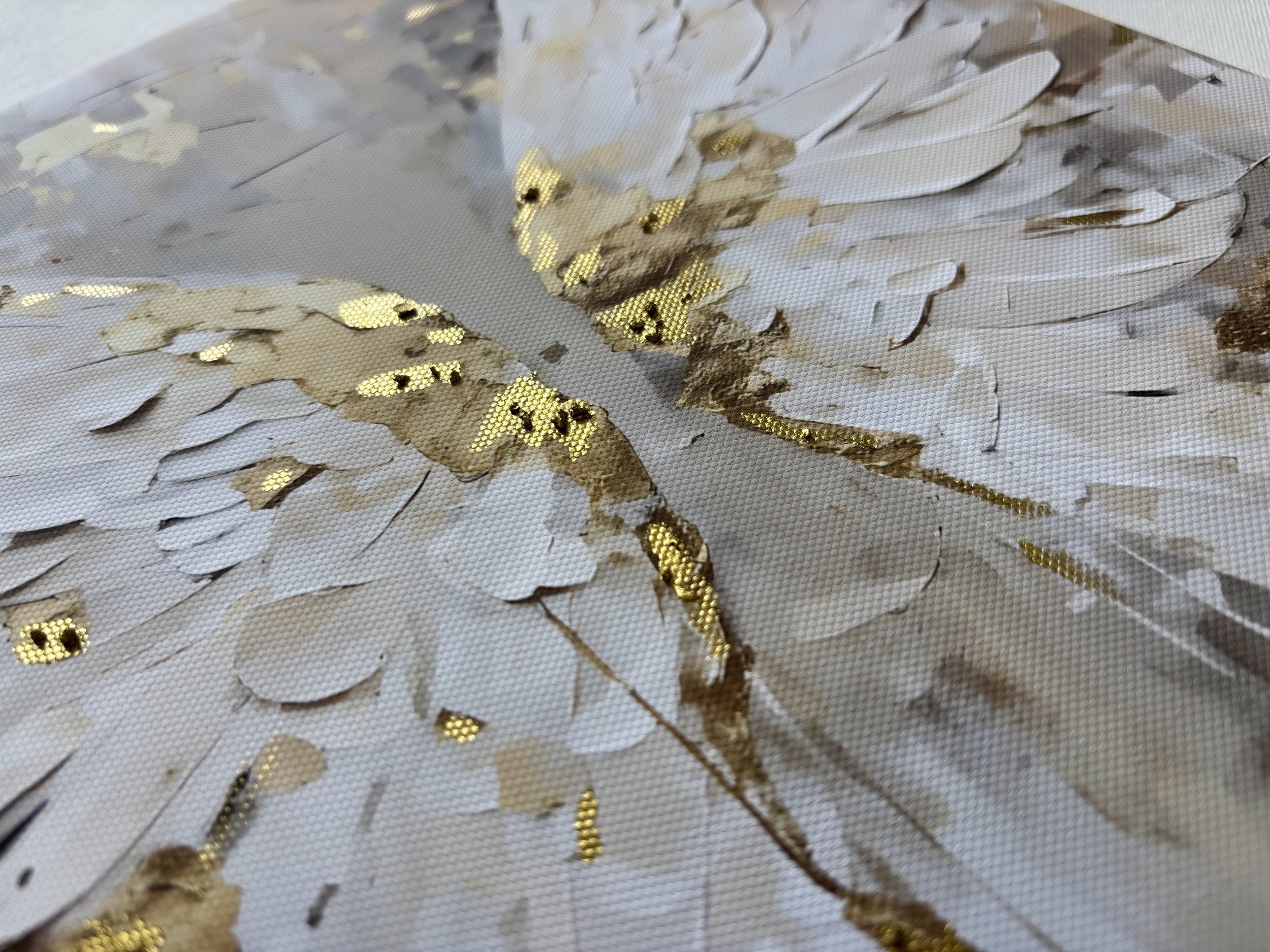 Close-up of a white floral pattern with gold accents on a textured fabric surface.