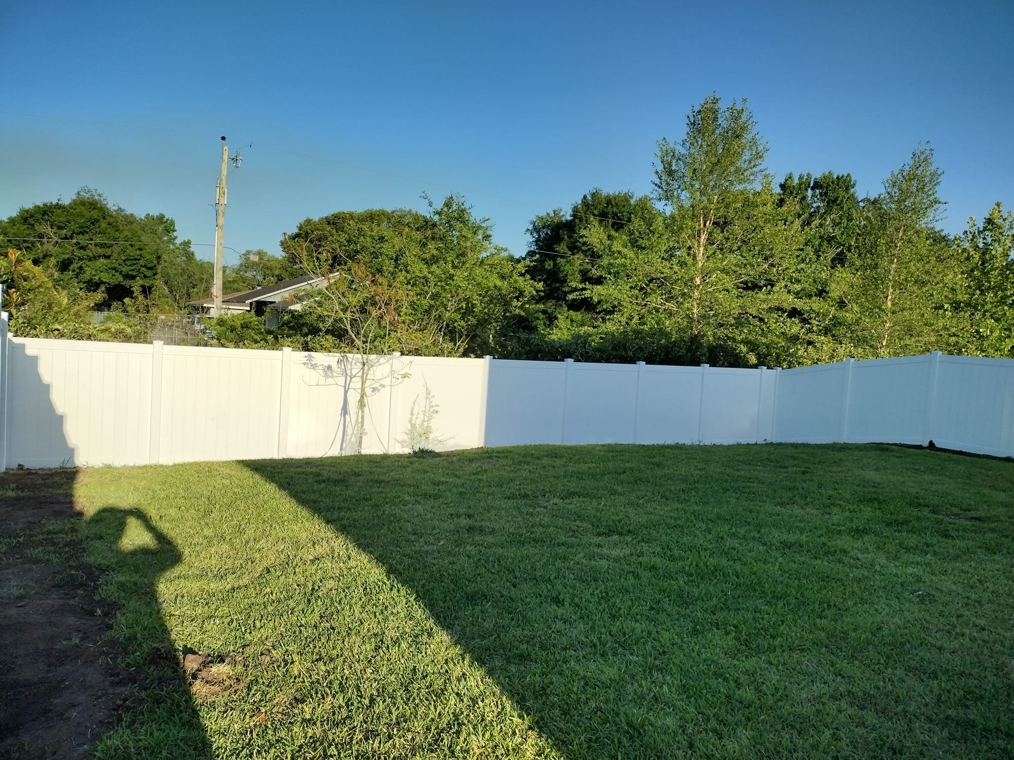 White vinyl fence enclosing green backyard lawn in Orlando Florida