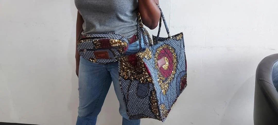 Person holding a large multicolored patterned tote bag and a small matching shoulder bag.