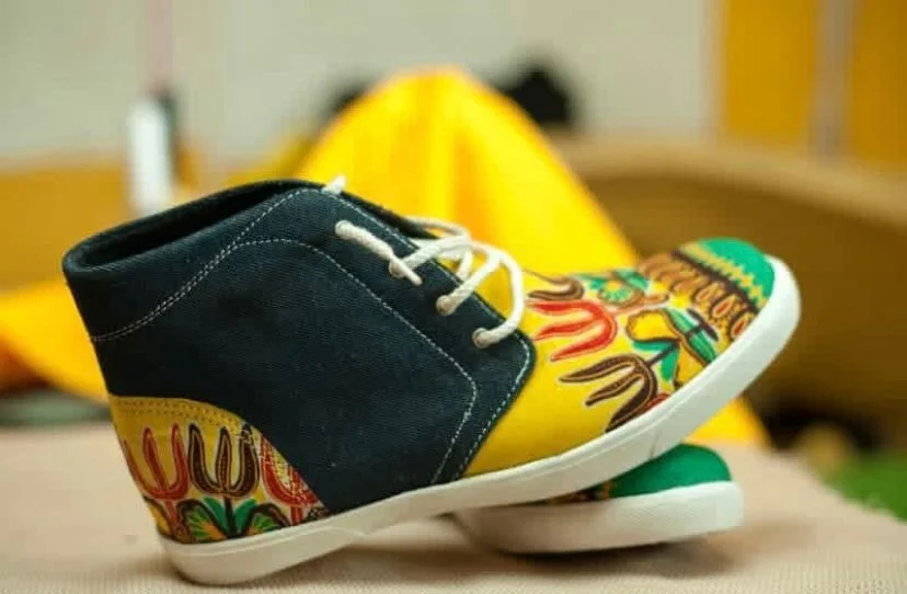 Colorful custom-designed sneakers with yellow, black, and floral patterns, placed on a flat surface with a blurred background.