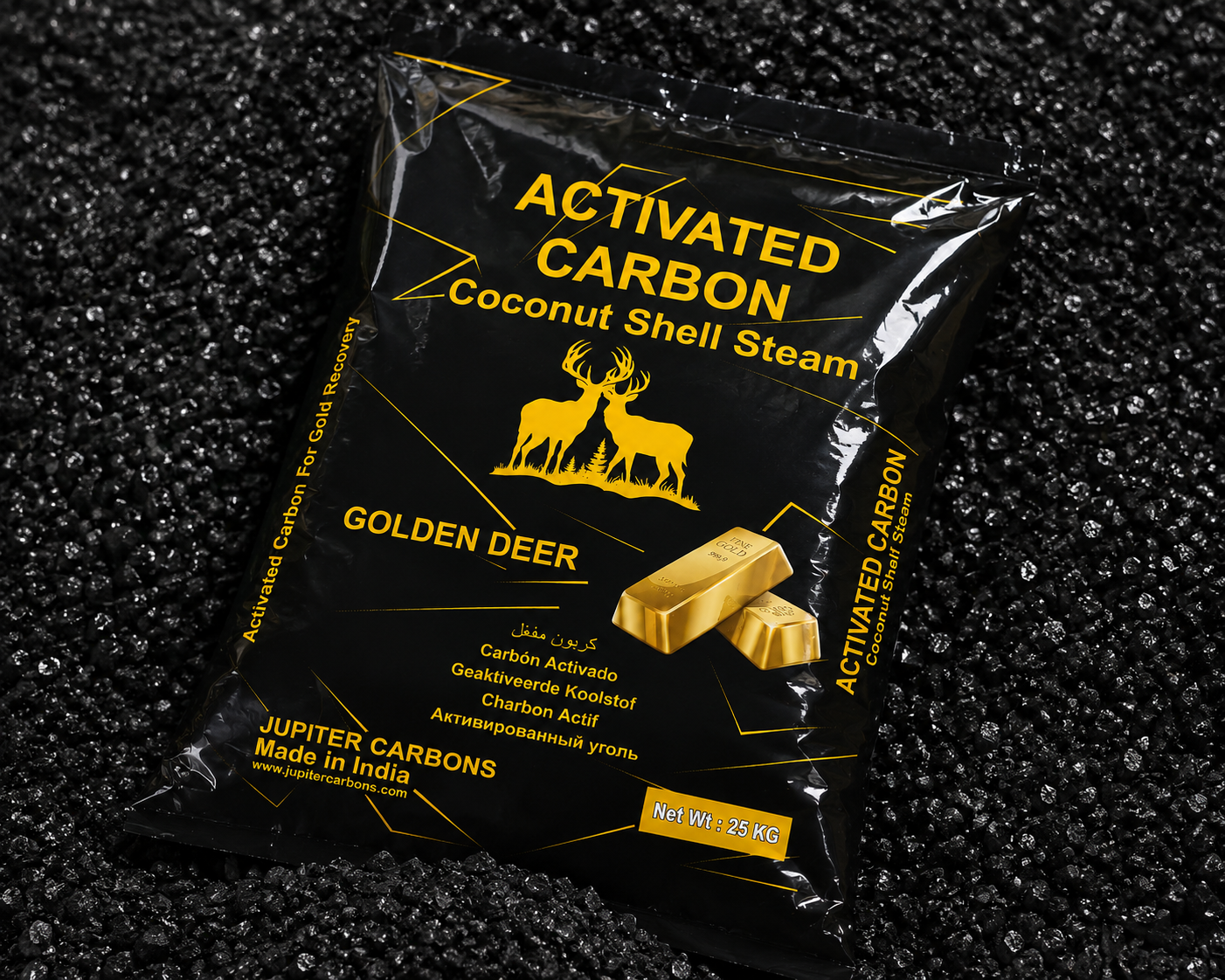 A black bag of activated carbon coconut shell steam with a gold deer logo and gold lettering, lying on a black textured surface. The bag contains 25 kilograms of product from Jupiter Carbons, made in India.
