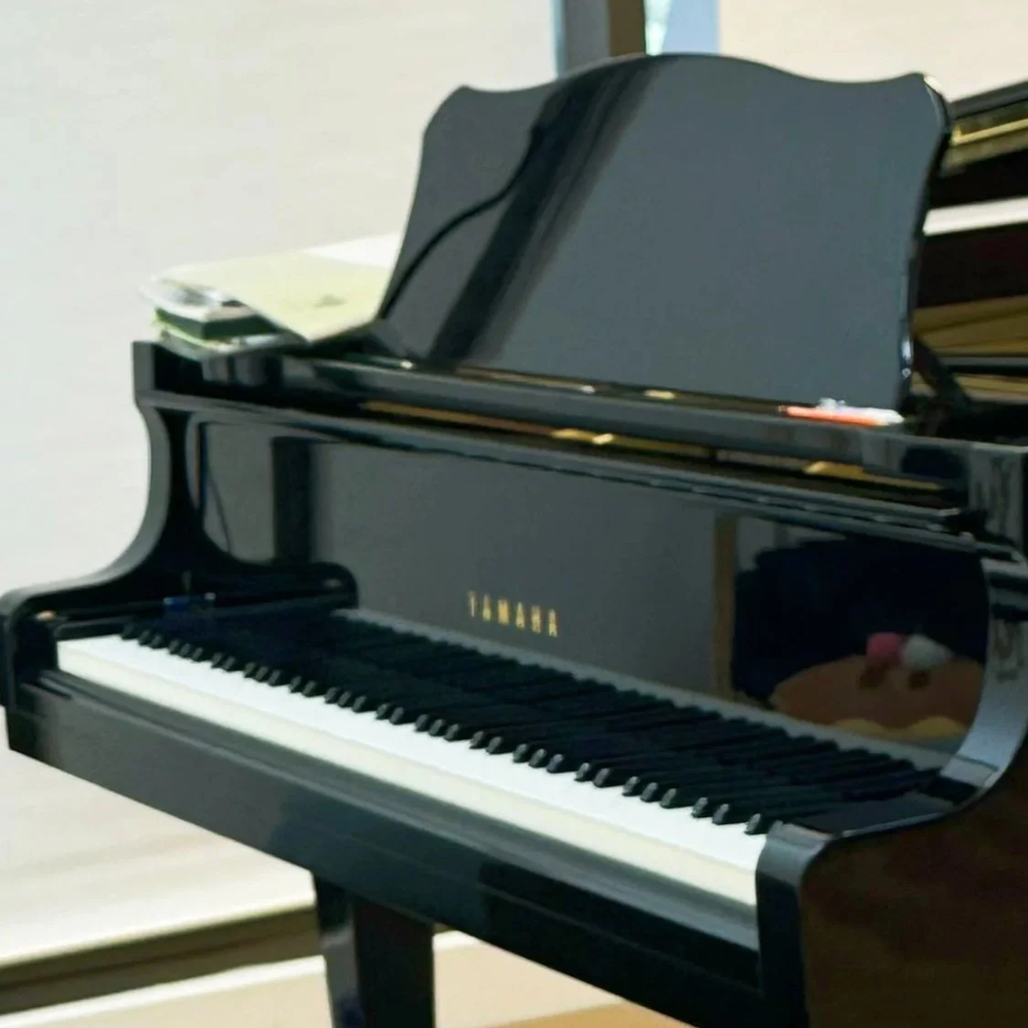 A black Yamaha grand piano with sheet music on the music stand in a music room.