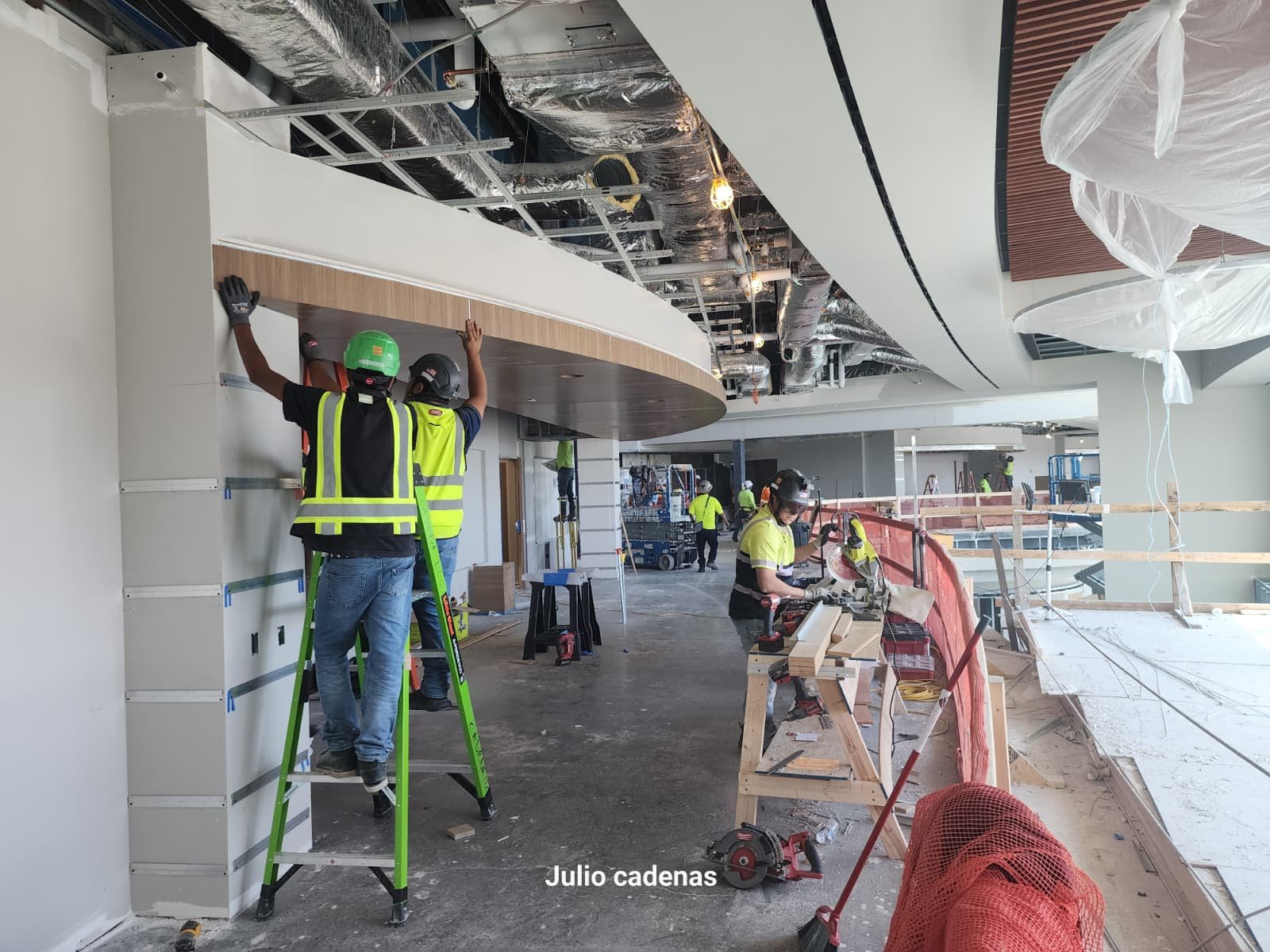 Construction workers installing ceiling panels and working on the interior framework of a building under construction.
