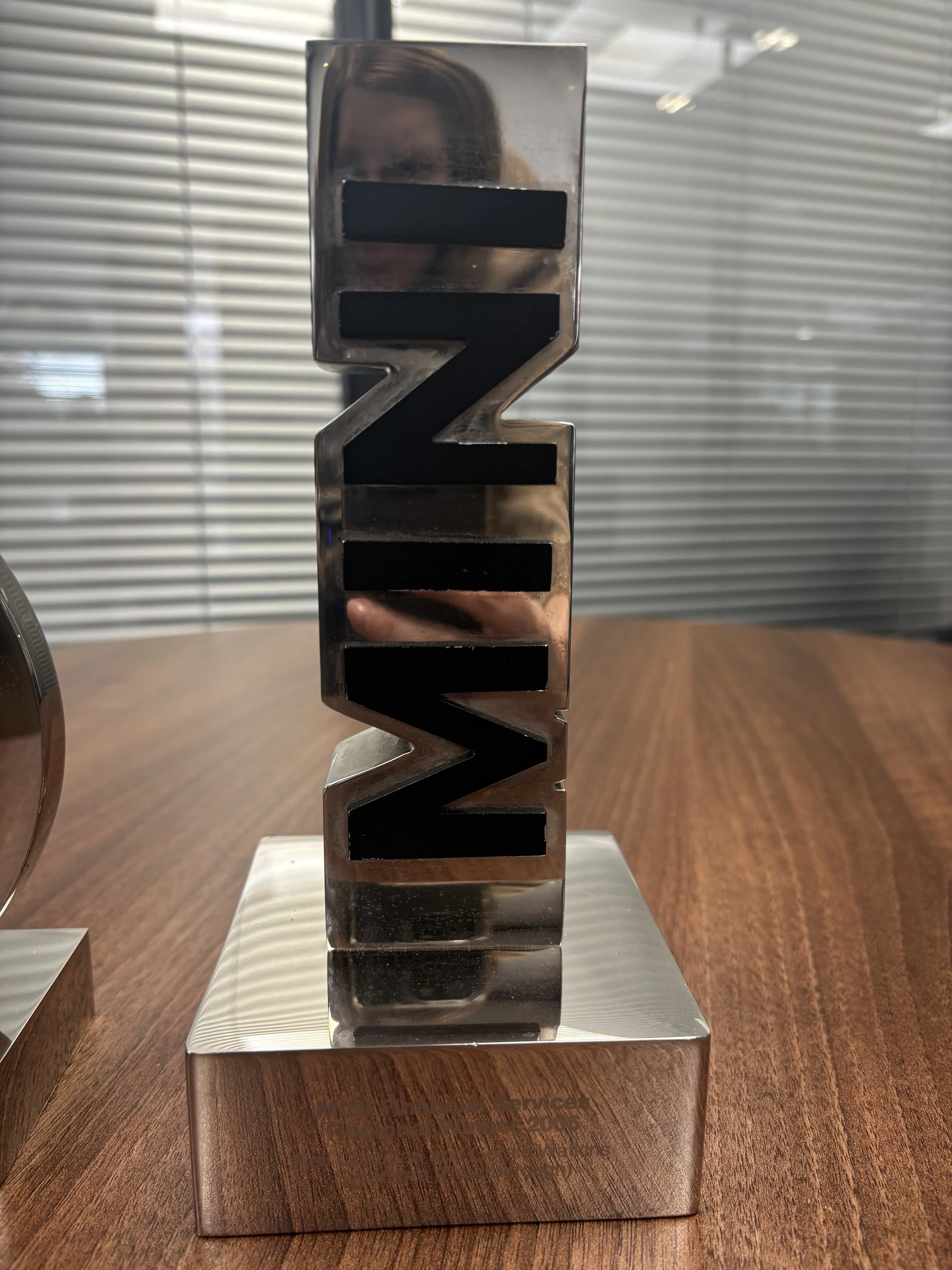 A metallic sculpture of the word 'Netflix' with each letter in a three-dimensional block style, standing on a wooden surface.