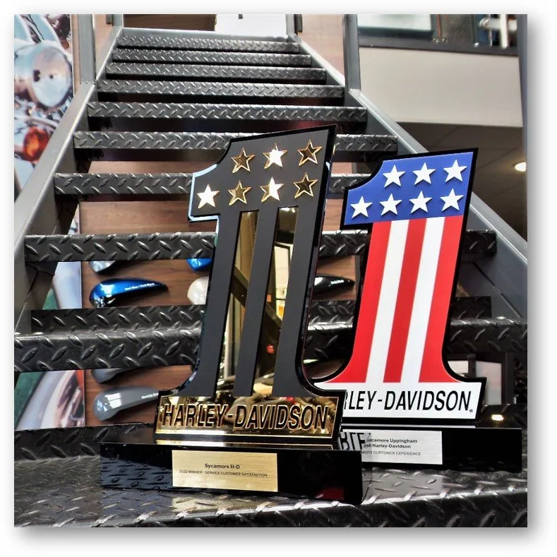 Harley-Davidson award trophies on a metal staircase with a motorcycle background.