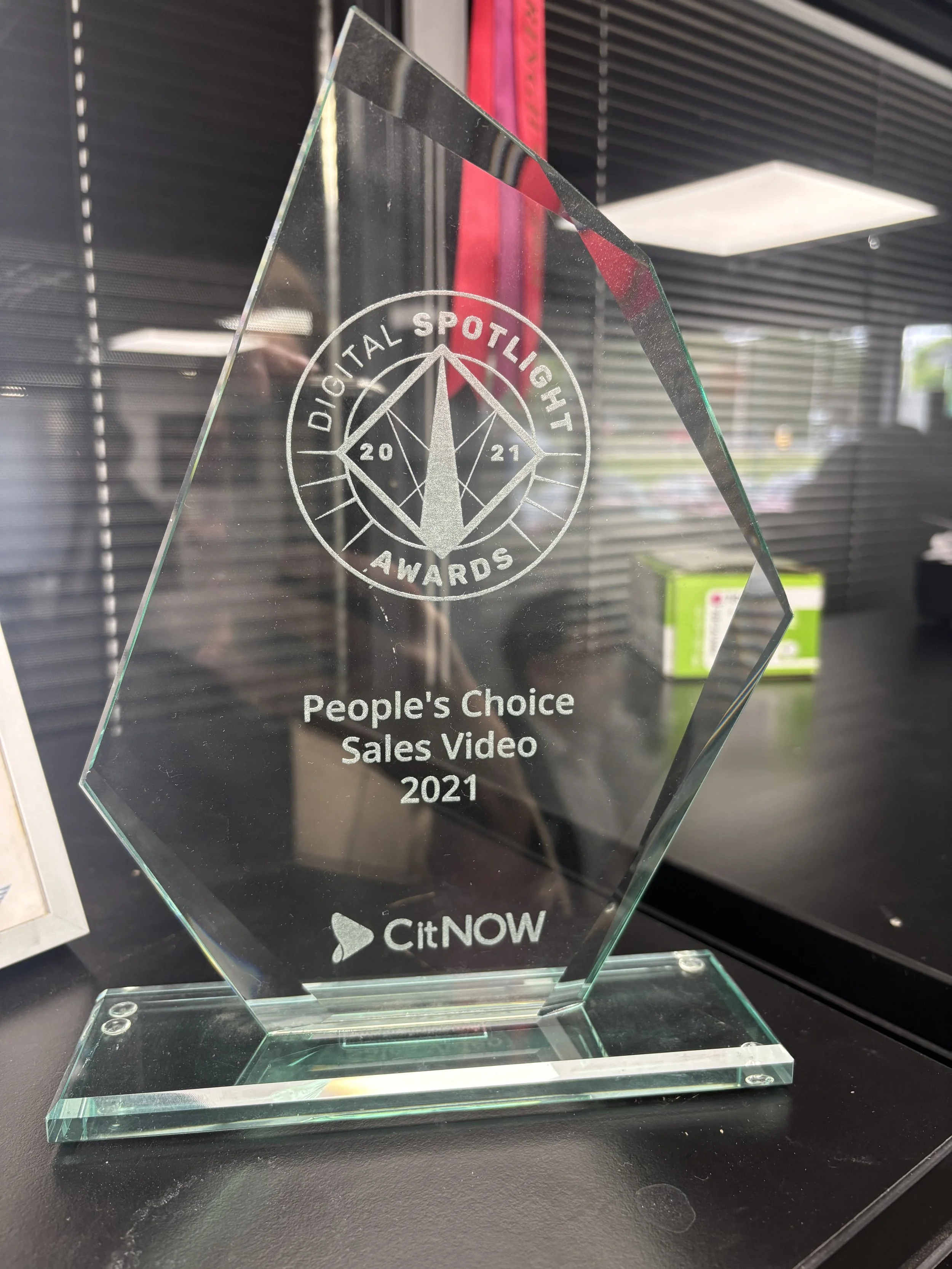 A glass award with the inscription 'Digital Spotlight Awards 2021 People's Choice Sales Video' and the logo 'citNOW', placed on a black surface with a reflective background.