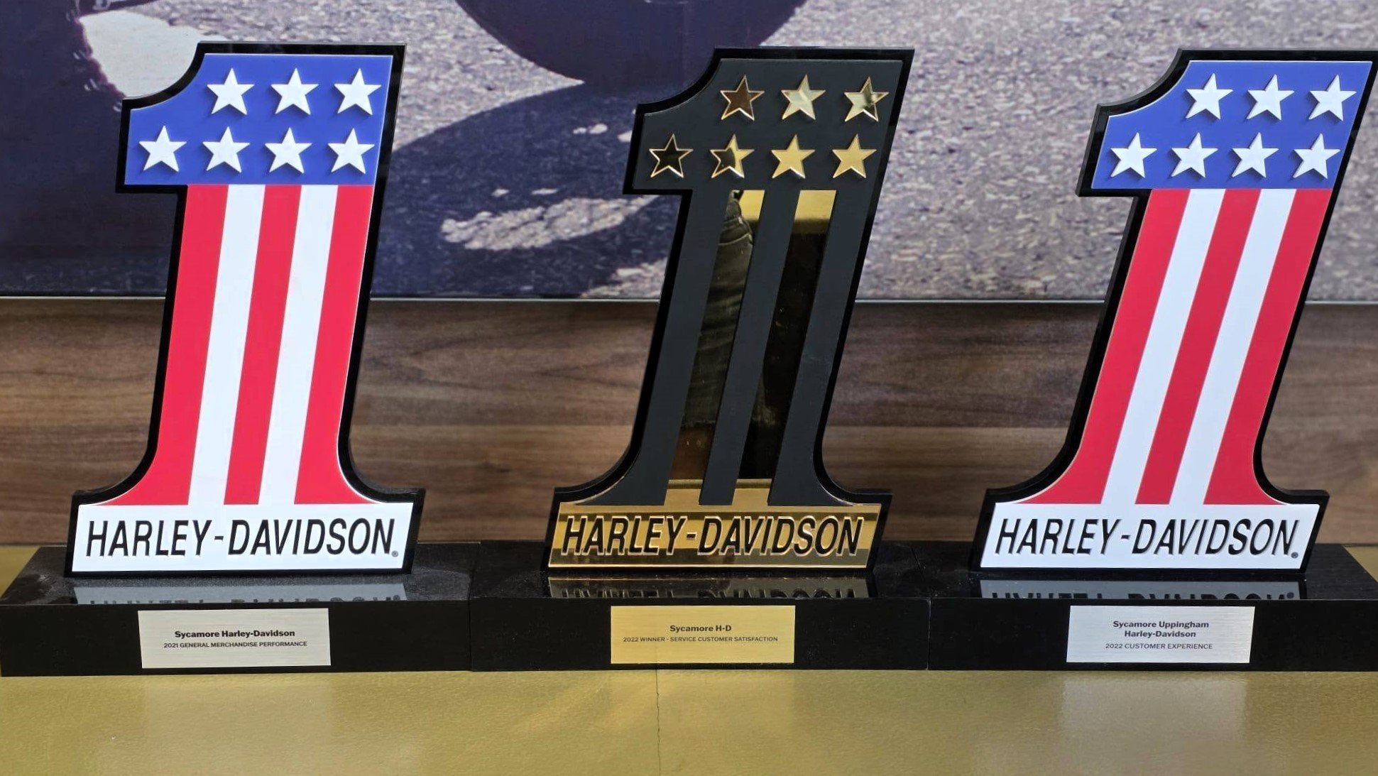 Three decorative Harley Davidson logos with patriotic theme, displayed on a table.