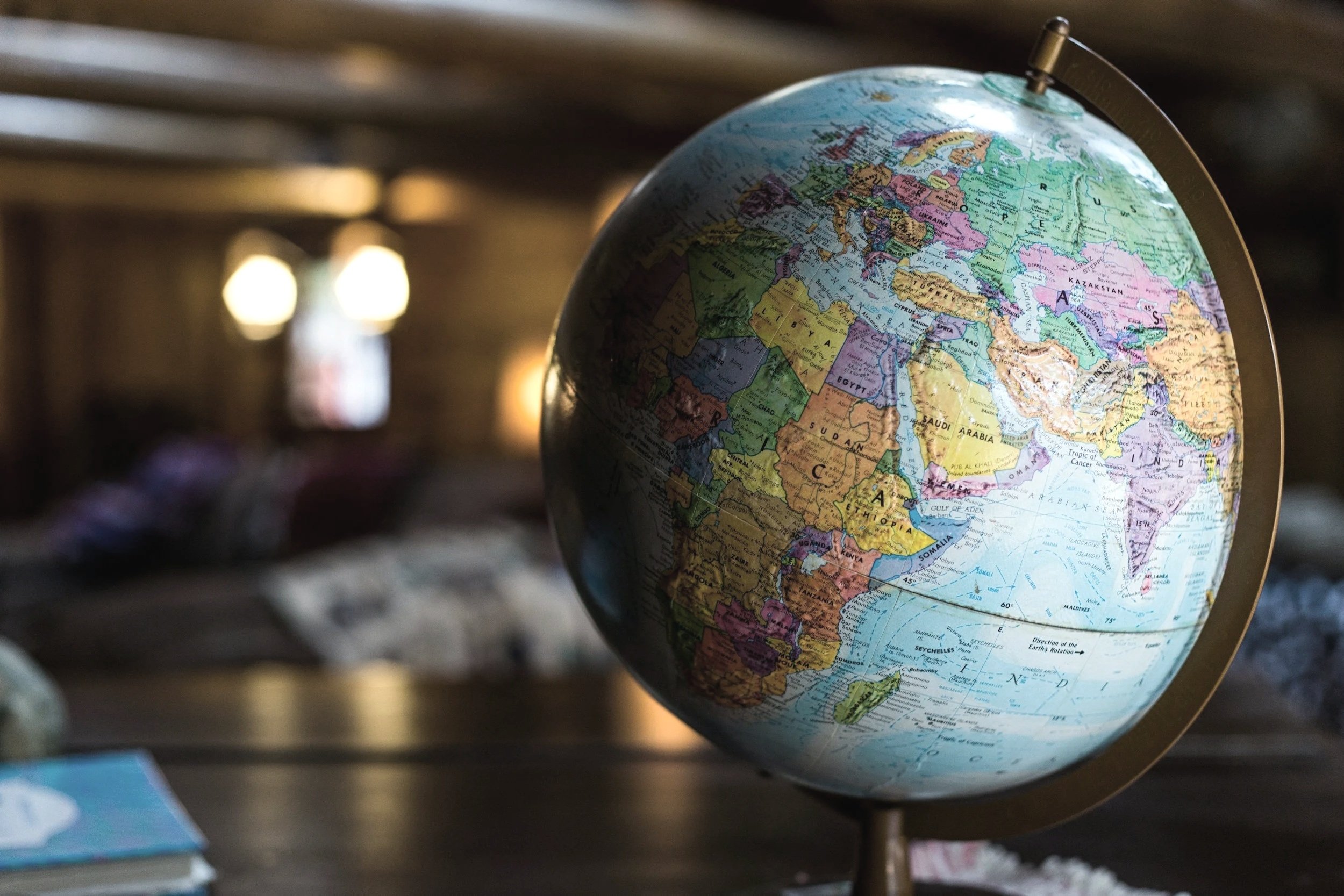 A globe showing Europe, Africa, and Asia, placed on a surface with blurred background.