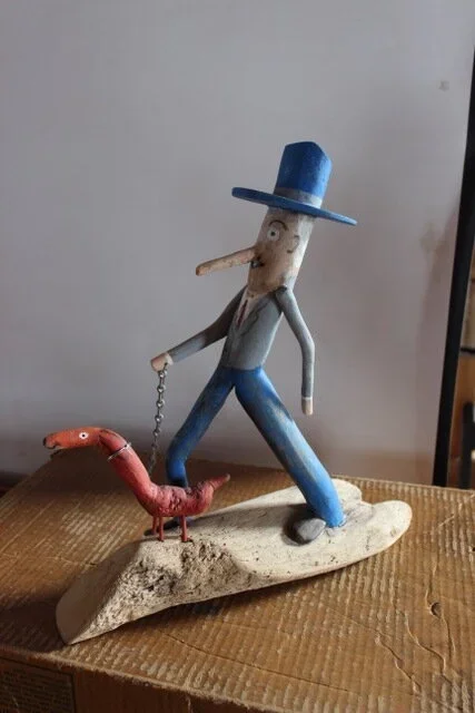 driftwood art of man walking a wiener dog