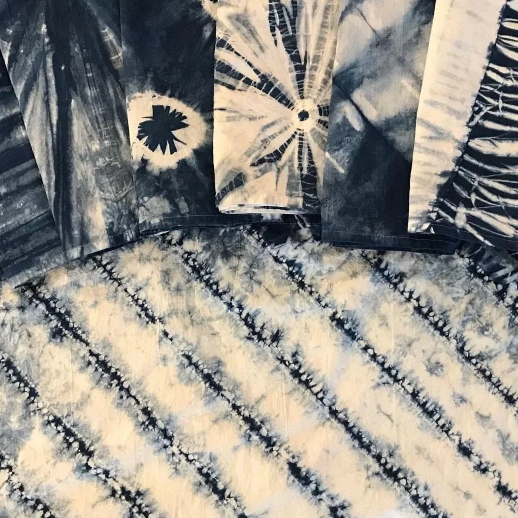 Close-up of a fabric with tie-dye pattern in blue and white, featuring various geometric and floral designs.