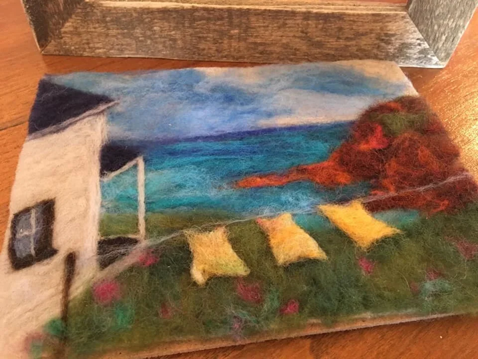 felted scene depicting a white house and  laundry on a line on the cape of pei