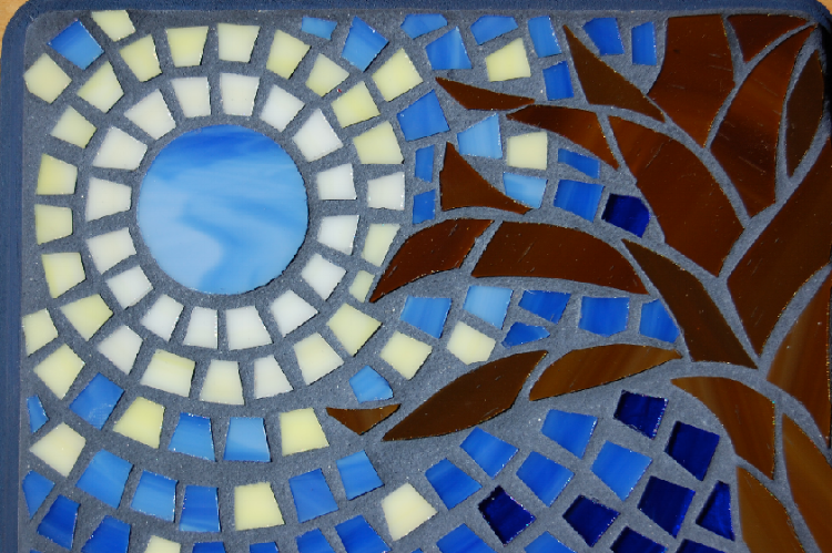 glass mosaic of the moon/sun and the shadow of a plant 
