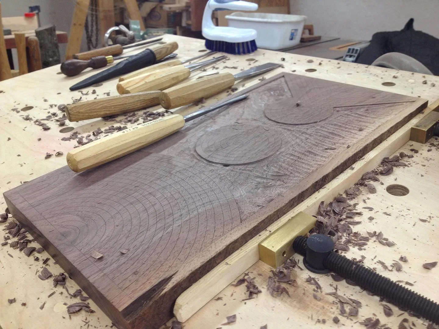 carving tools and a partially carved wall hanging