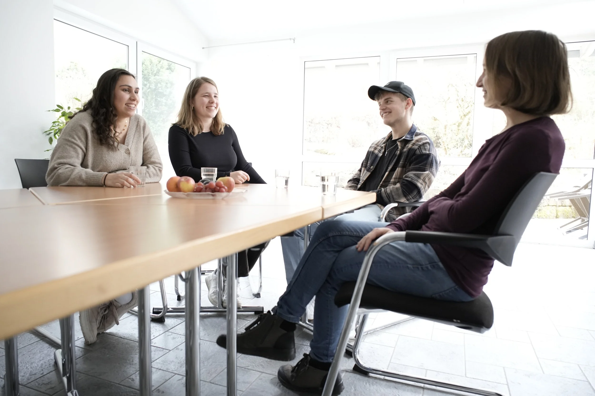 Vier Menschen, Besprechung, lockere Atmosphäre, Obst auf dem Tisch