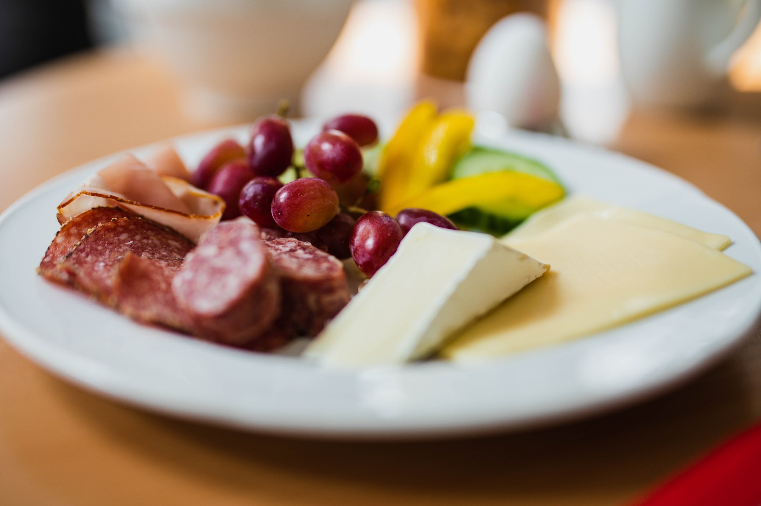 Frühstücksteller mit Käse, Schinken, Trauben und Gemüsesticks