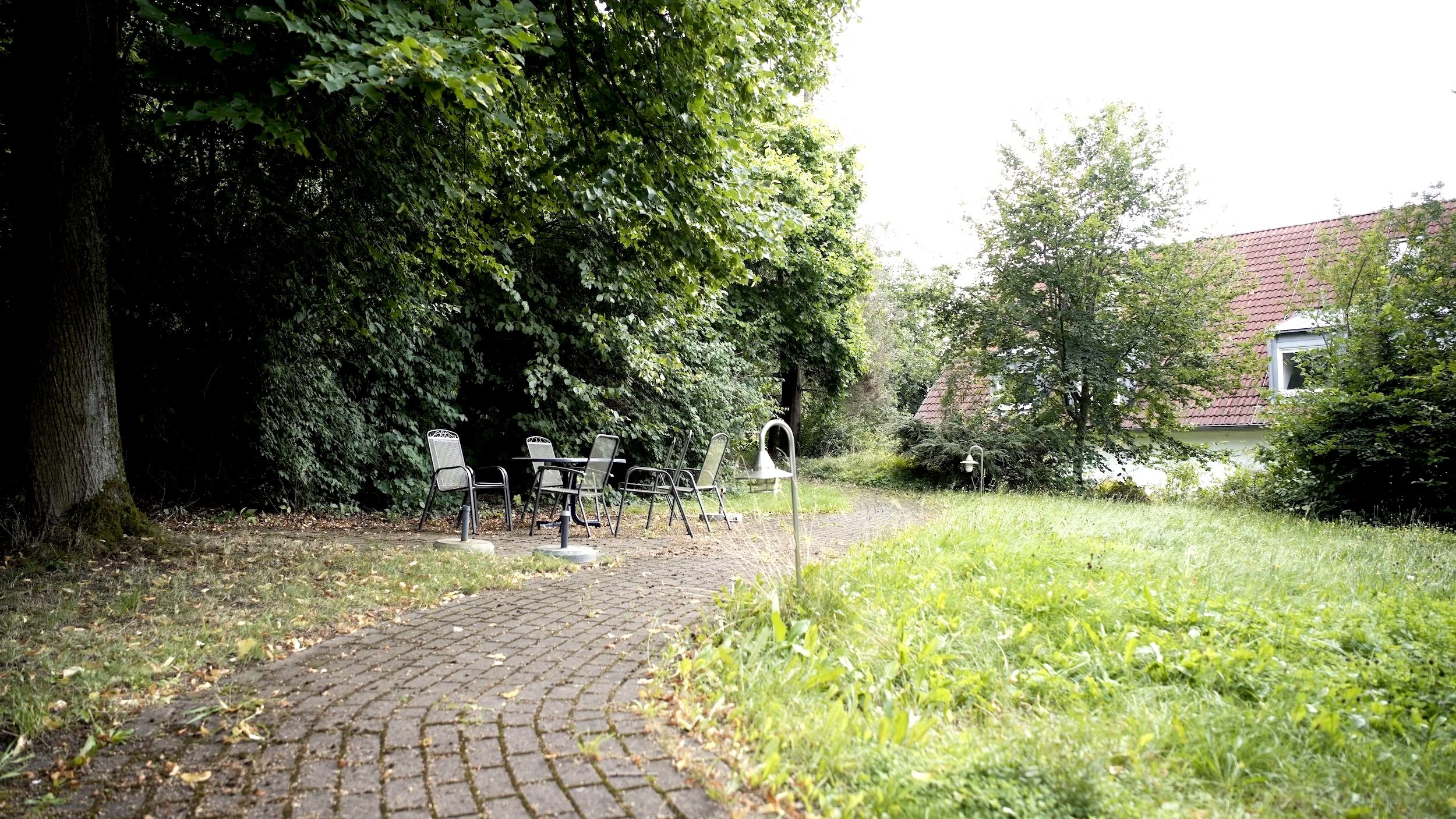 Garten des Gästehauses Tabor, Haus 2. Bäume, Wiese, Fußweg, Sitzecke.
