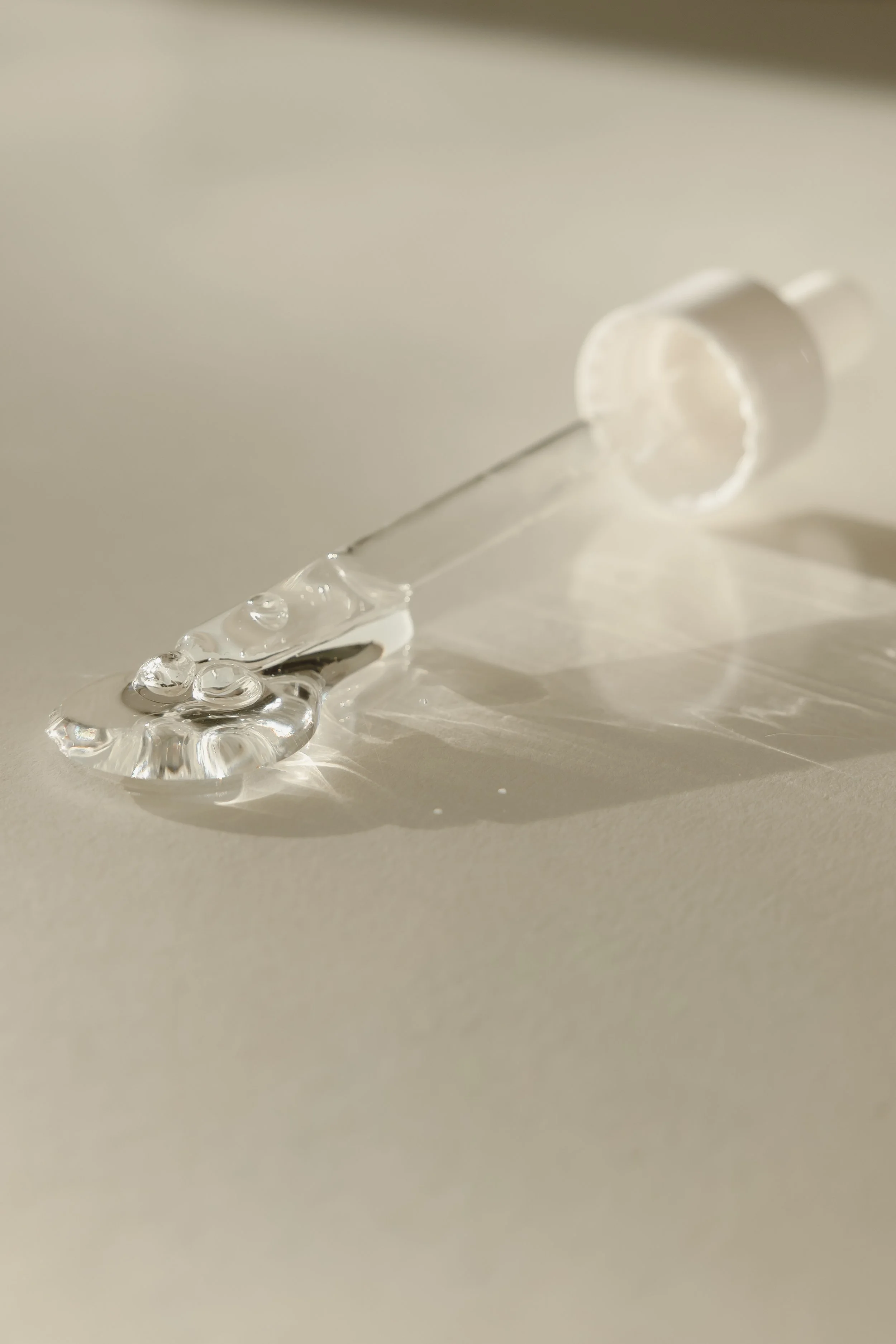Close-up of a glass syringe with a needle lying on a flat surface, casting a shadow.