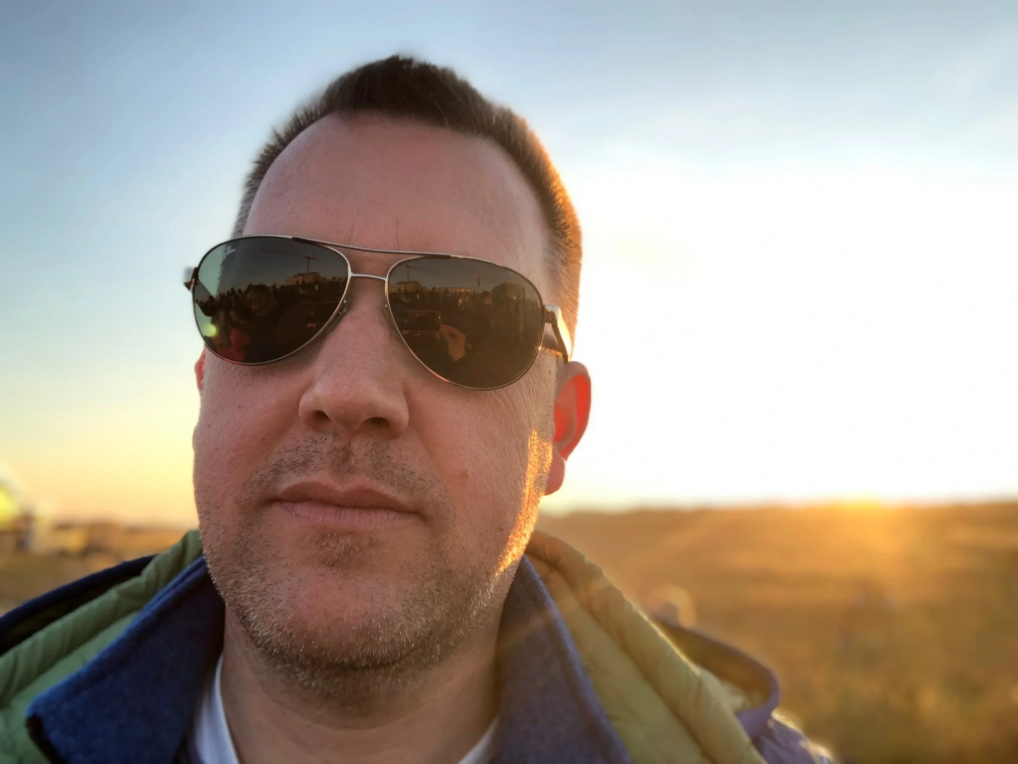 Nahaufnahme eines Mannes mit Sonnenbrille bei Sonnenuntergang im Freien.
