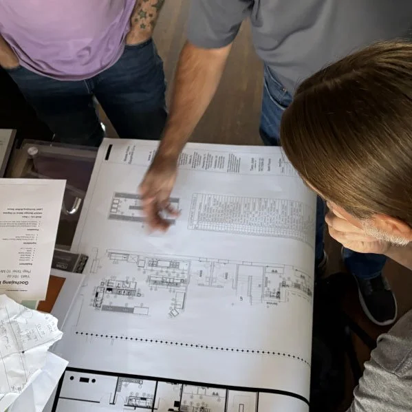 People reviewing architectural blueprints on a table.