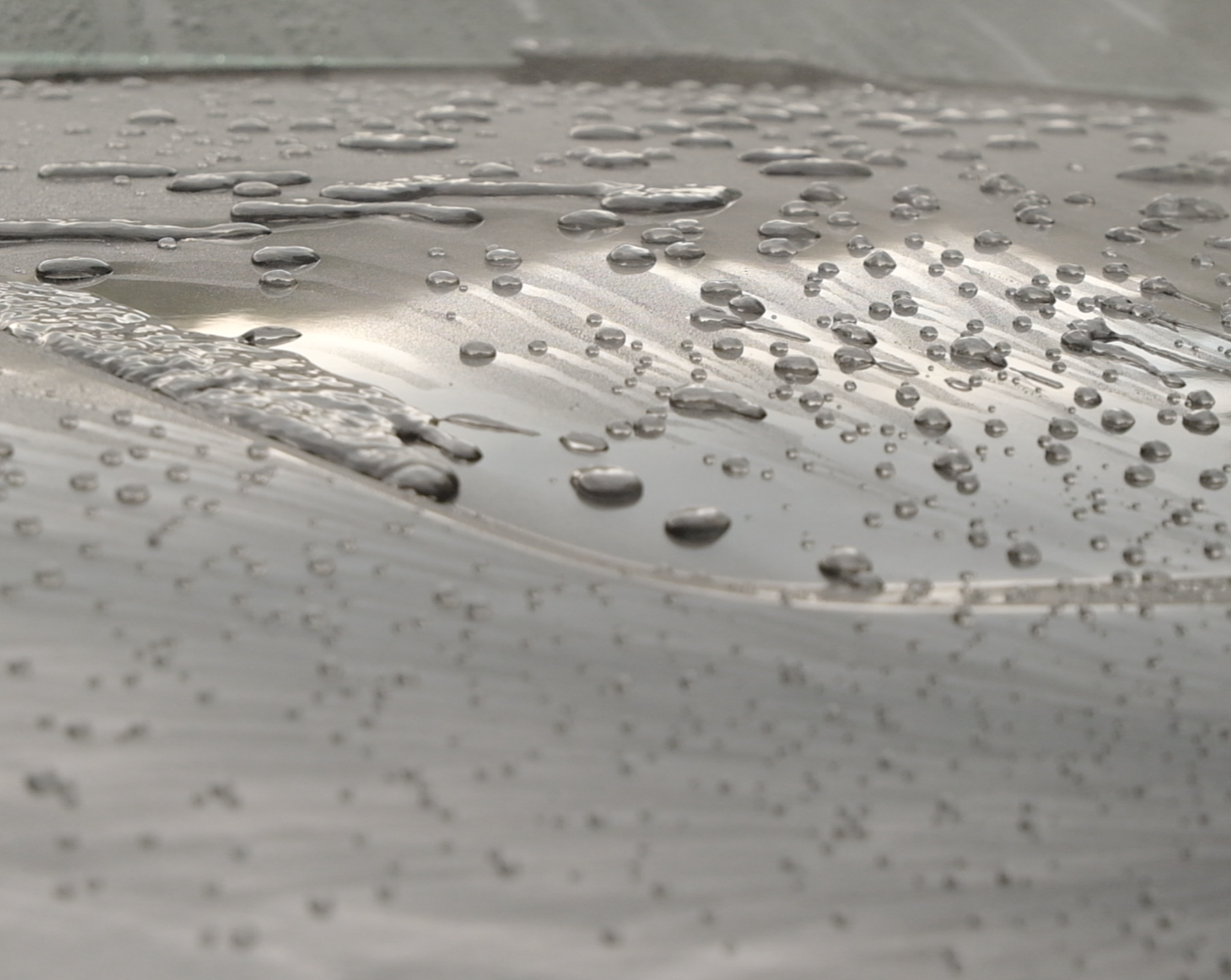 Close-up of a metallic surface with water droplets scattered across it.