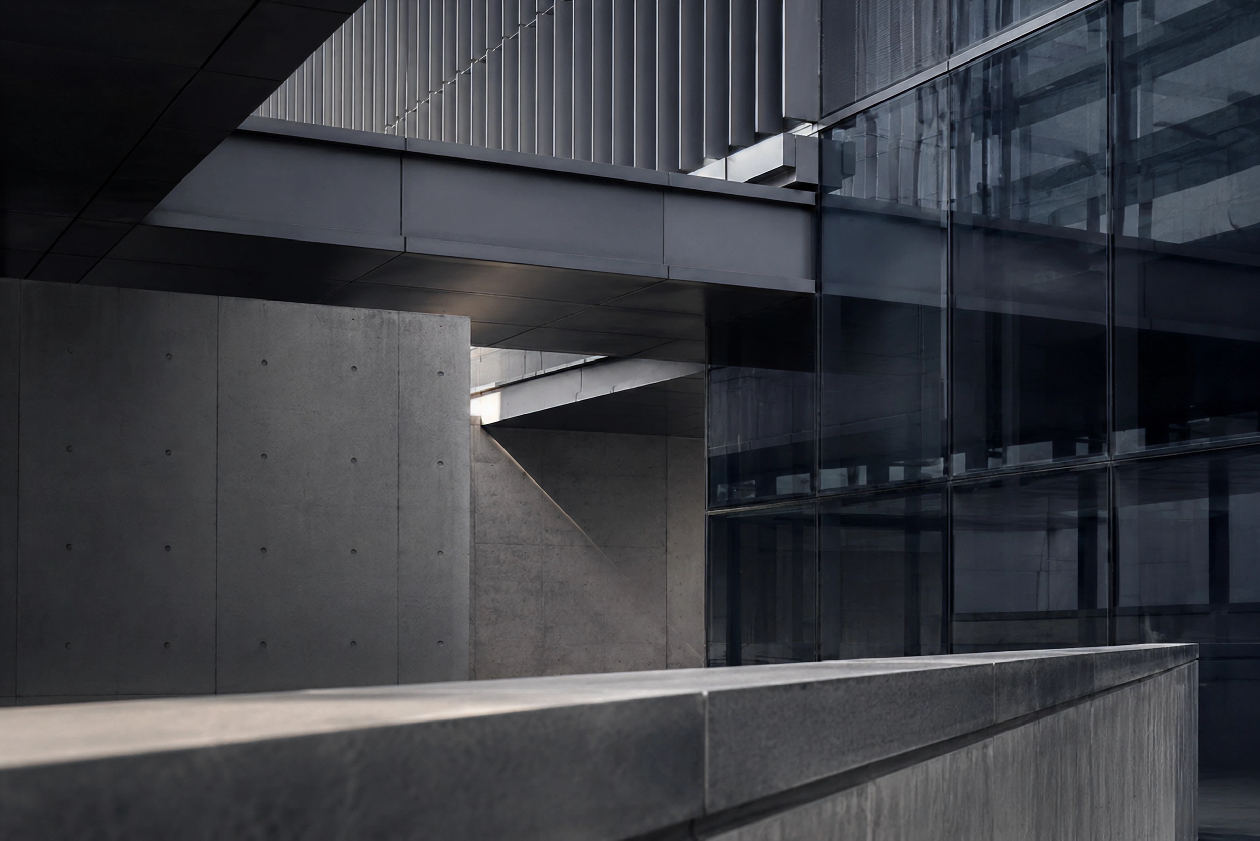 Close-up of a modern building with glass windows, metal panels, and concrete, featuring geometric lines and architecture.