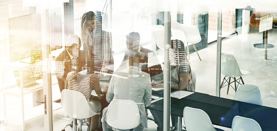 People having a business meeting in a modern office with large glass windows and city view.