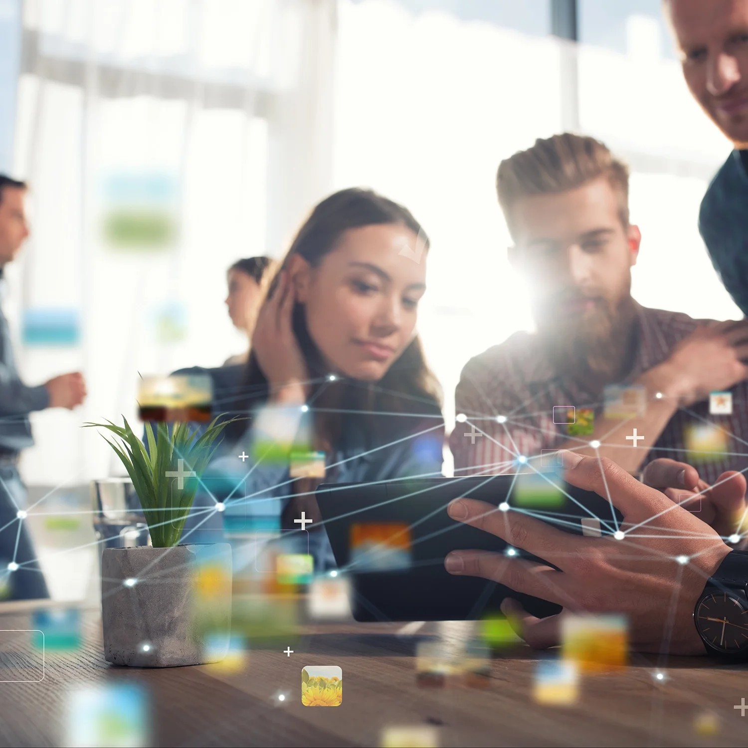 A group of young professionals working together at a table with a digital overlay of interconnected icons and lines, symbolizing technology and networking.