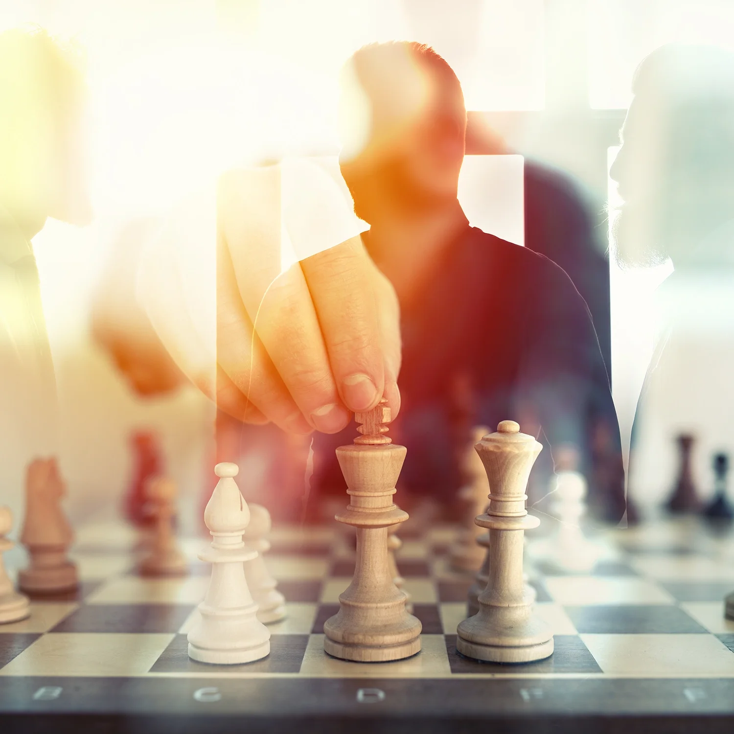 A person moving a chess piece on a chessboard, with other chess pieces around.