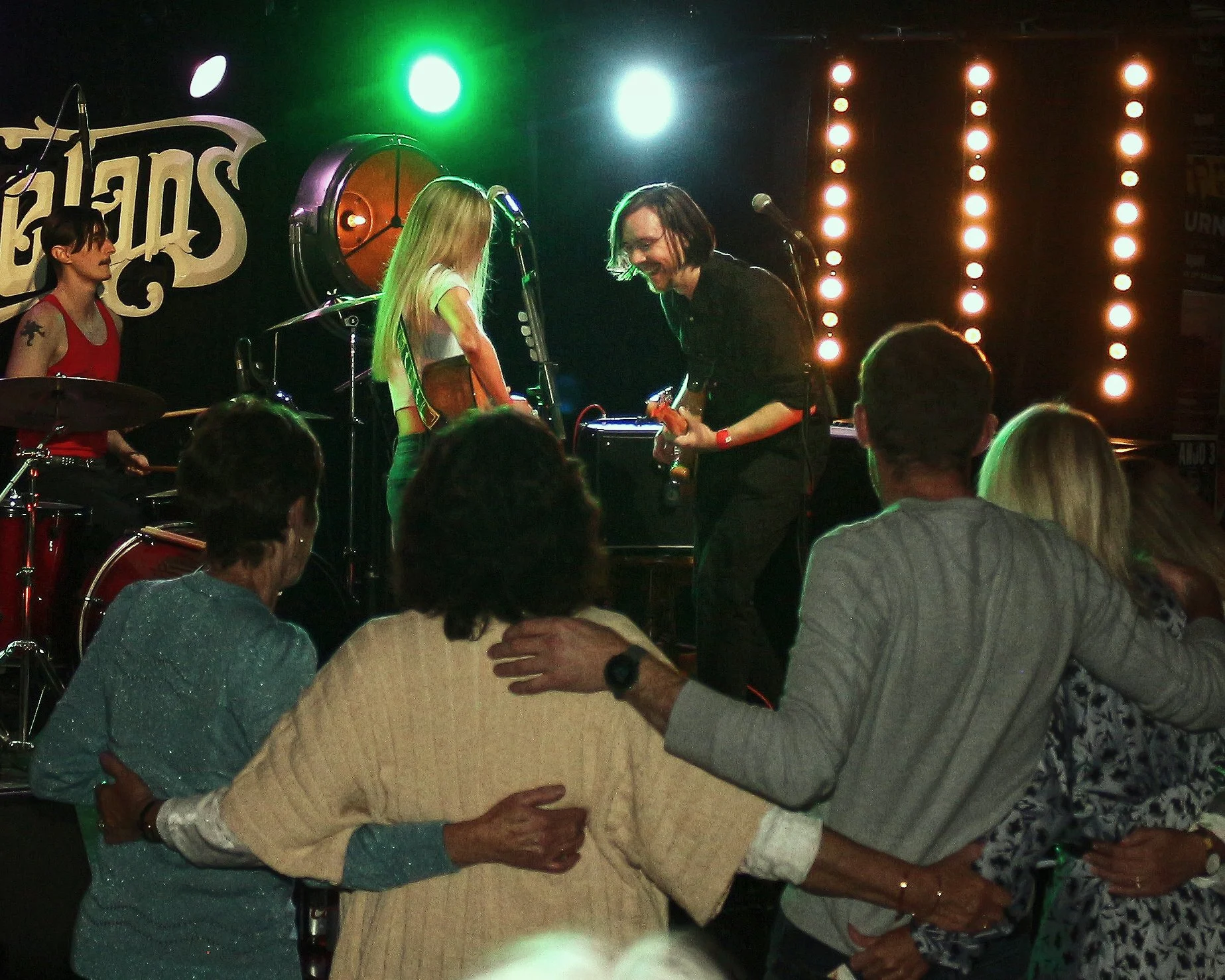 A live music performance with a band on stage and an audience enjoying the show.