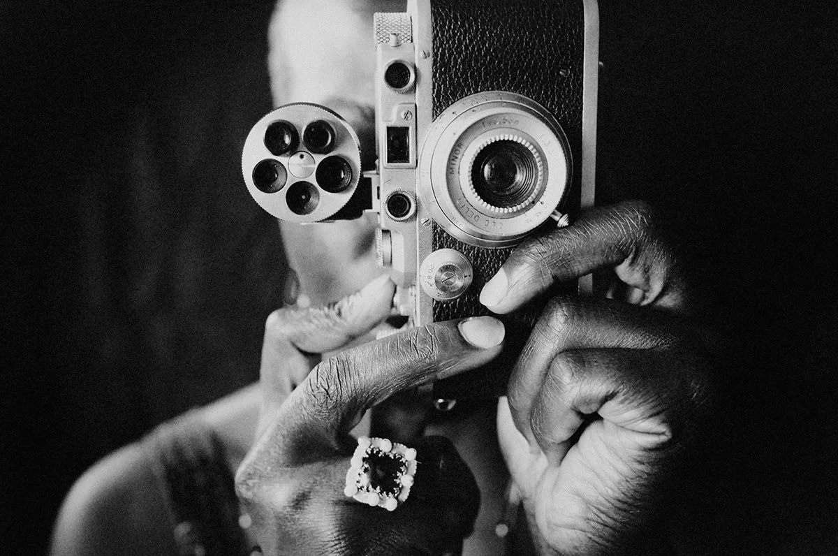 Photographer holding a vintage camera. Monochrome portrait representing observation, storytelling and the photographic process.