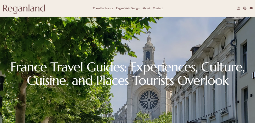 Screenshot of the Reganland homepage, a France travel website featuring a tree-lined street and historic church.
